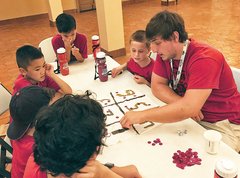 Education Intern Student teacher with a group of young students around a table