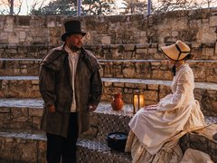 Living historian seated on steps with a lantern