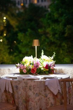 Floral centerpiece on a floral linen on a cocktail table set on an outside terrace