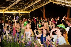 Dance floor full of wedding guests in black tie attire dancing under string lighting